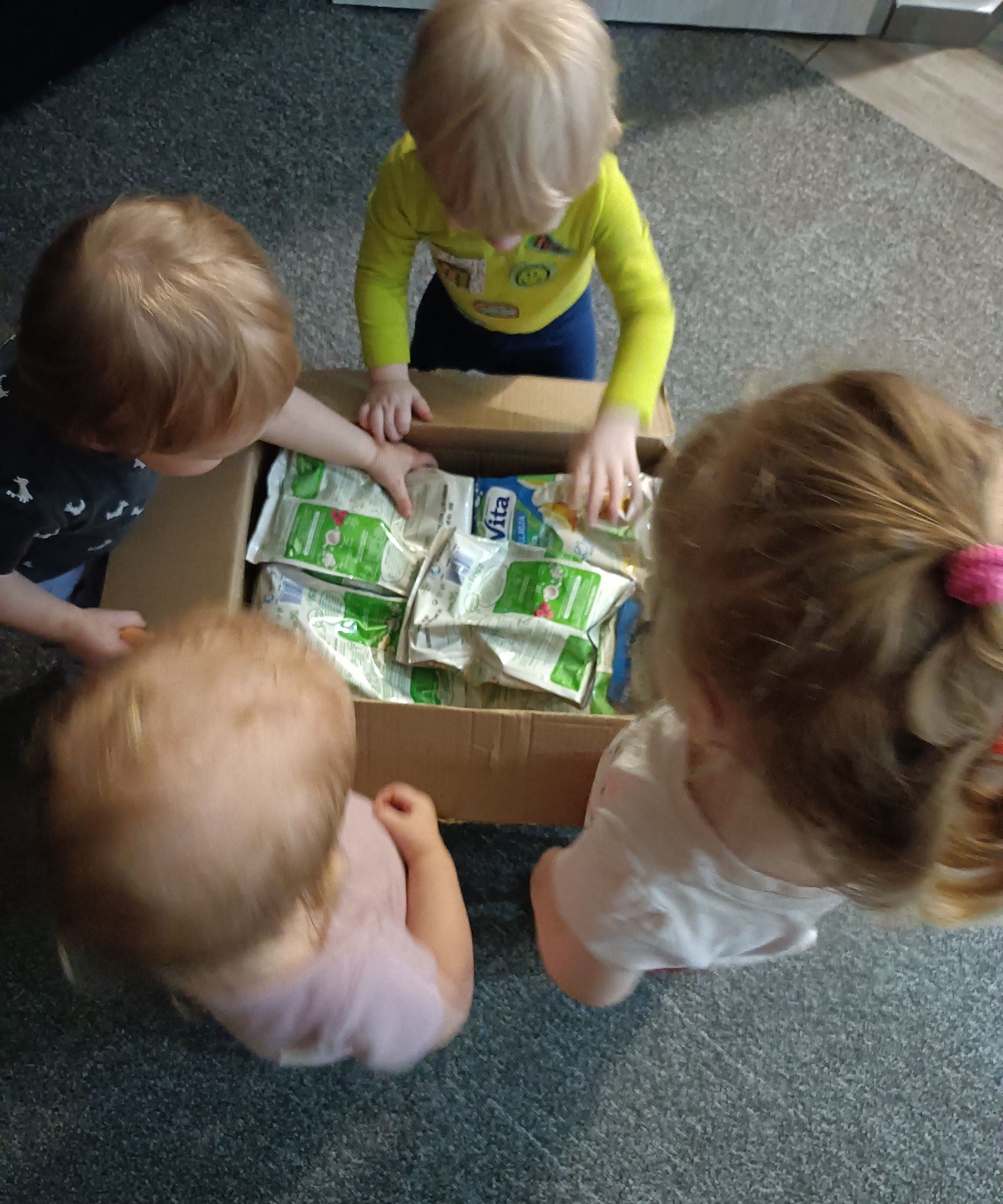 Maluchy otwierające karton z pieluchami